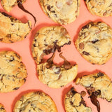 Choc Chip New York Cookie by Crumbs & Doilies with gooey dark and milk chocolate chunks on a peach background.